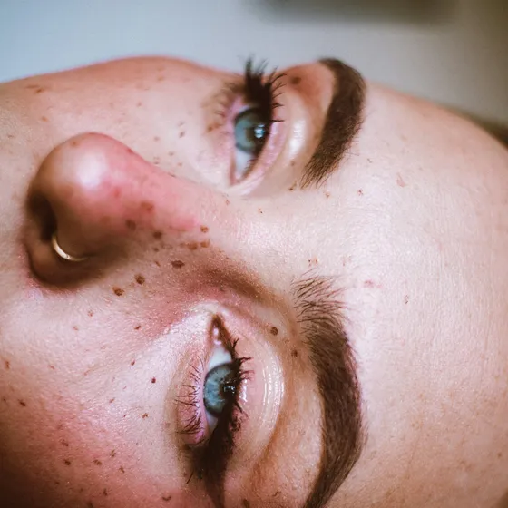 Close portrait of a woman with freckles, defined brows and lifted lashes