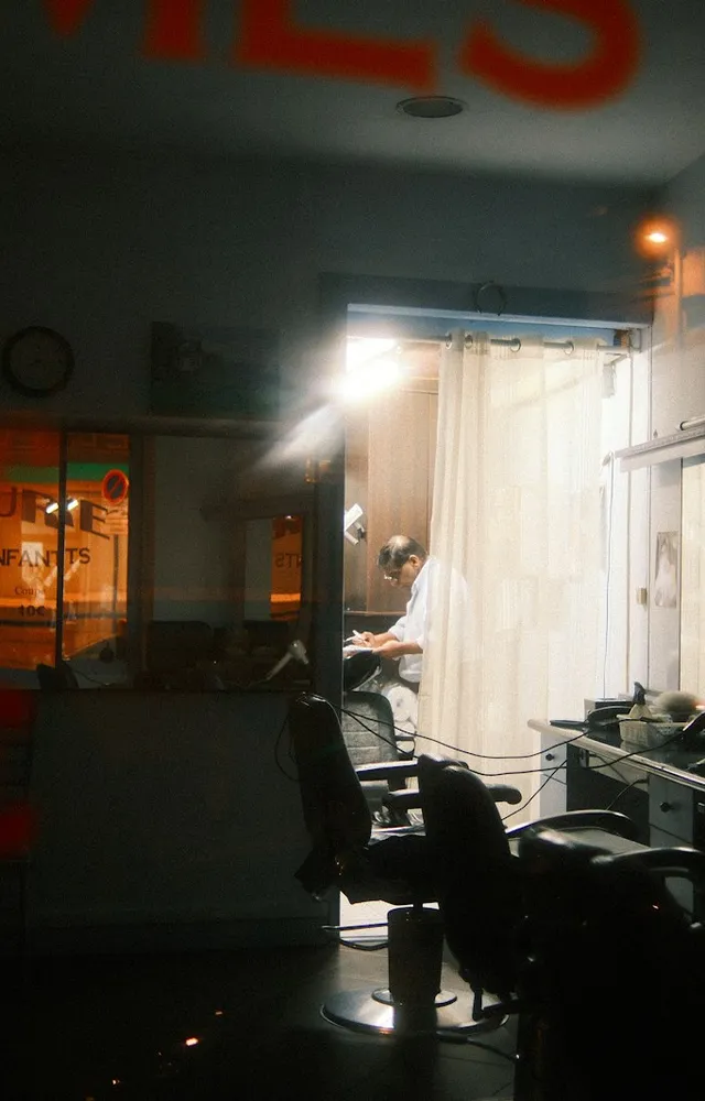 Looking through a salon front window at night, warm lights inside