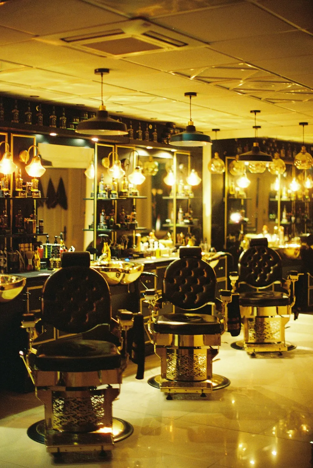 Rows of leather barber chairs under warm hanging lights
