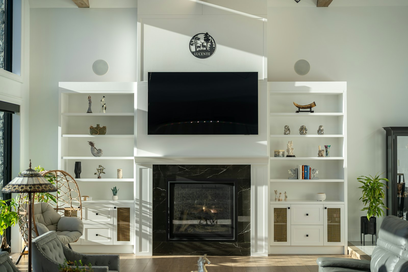 White fireplace wall with TV, black marble surround and built-in shelves and cabinets on both sides