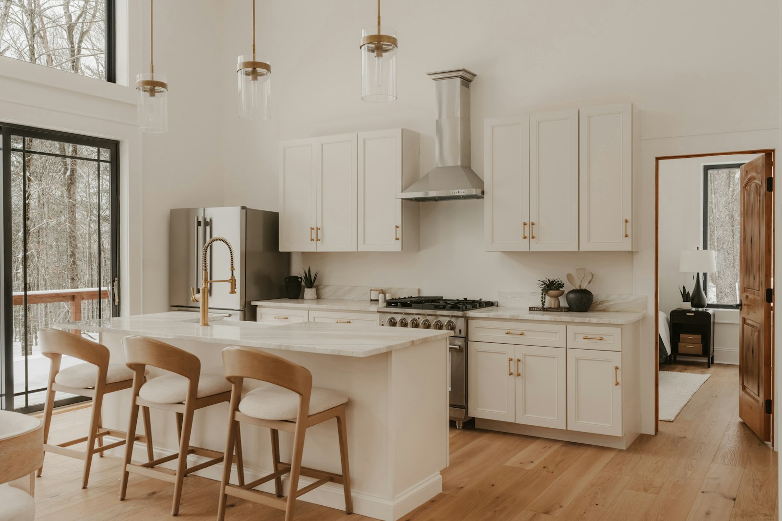 White kitchen island with stone countertop, pendant lights and wood bar stools