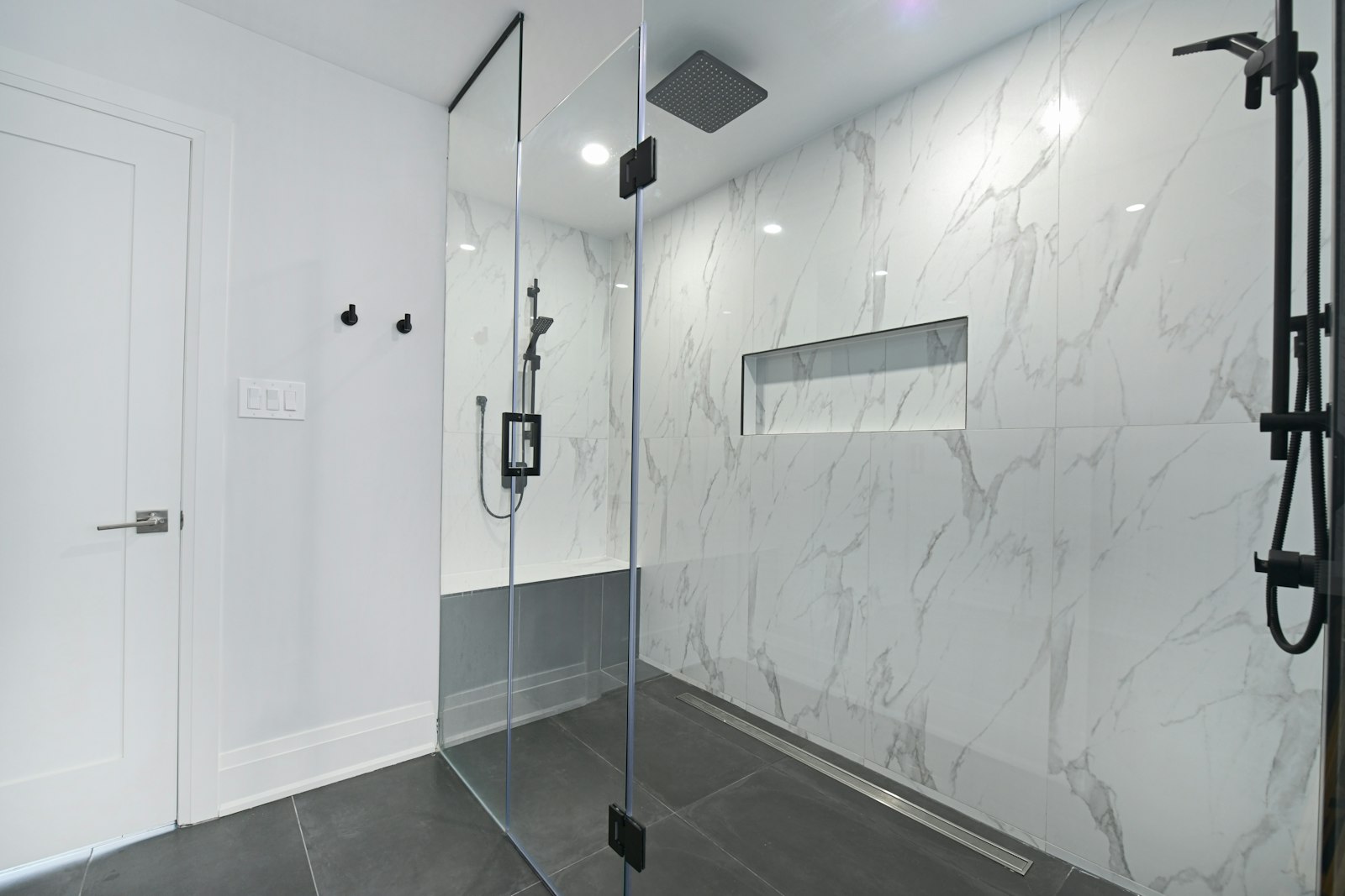 Walk-in shower with marble look tile, a long niche and a glass enclosure