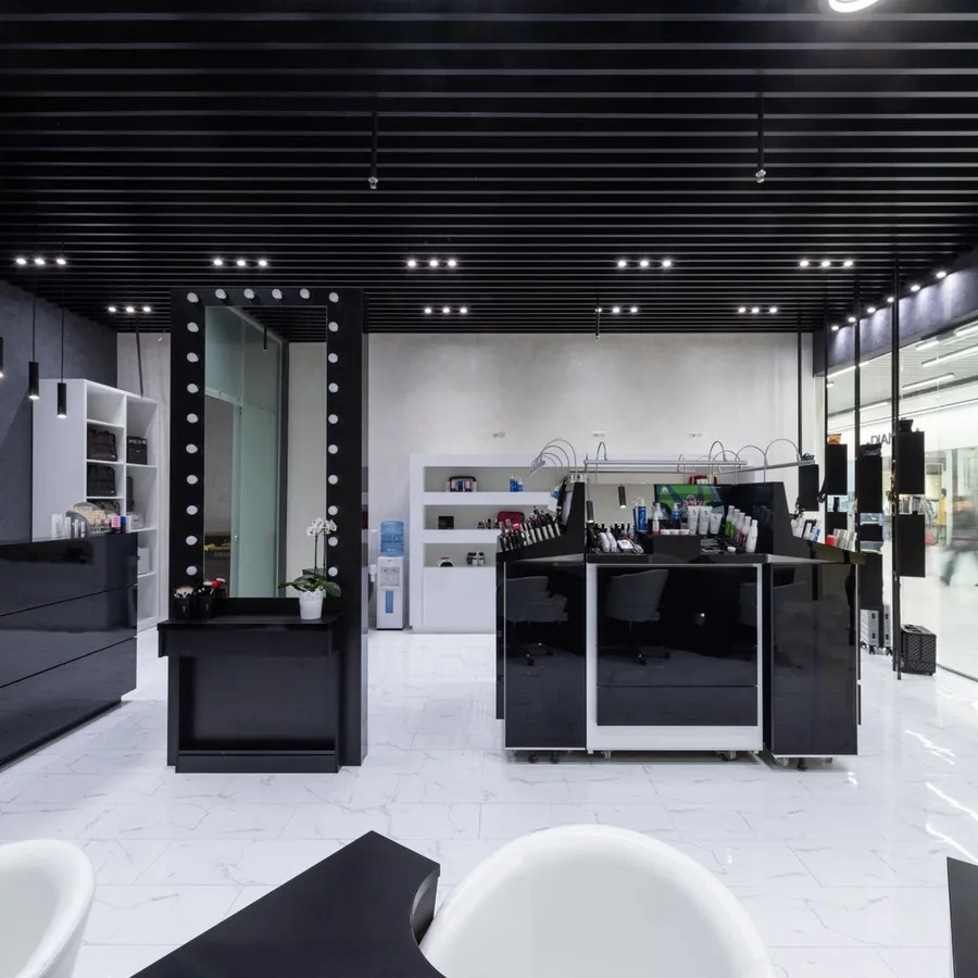 A modern reception area with a black counter, white floors and lit mirrors