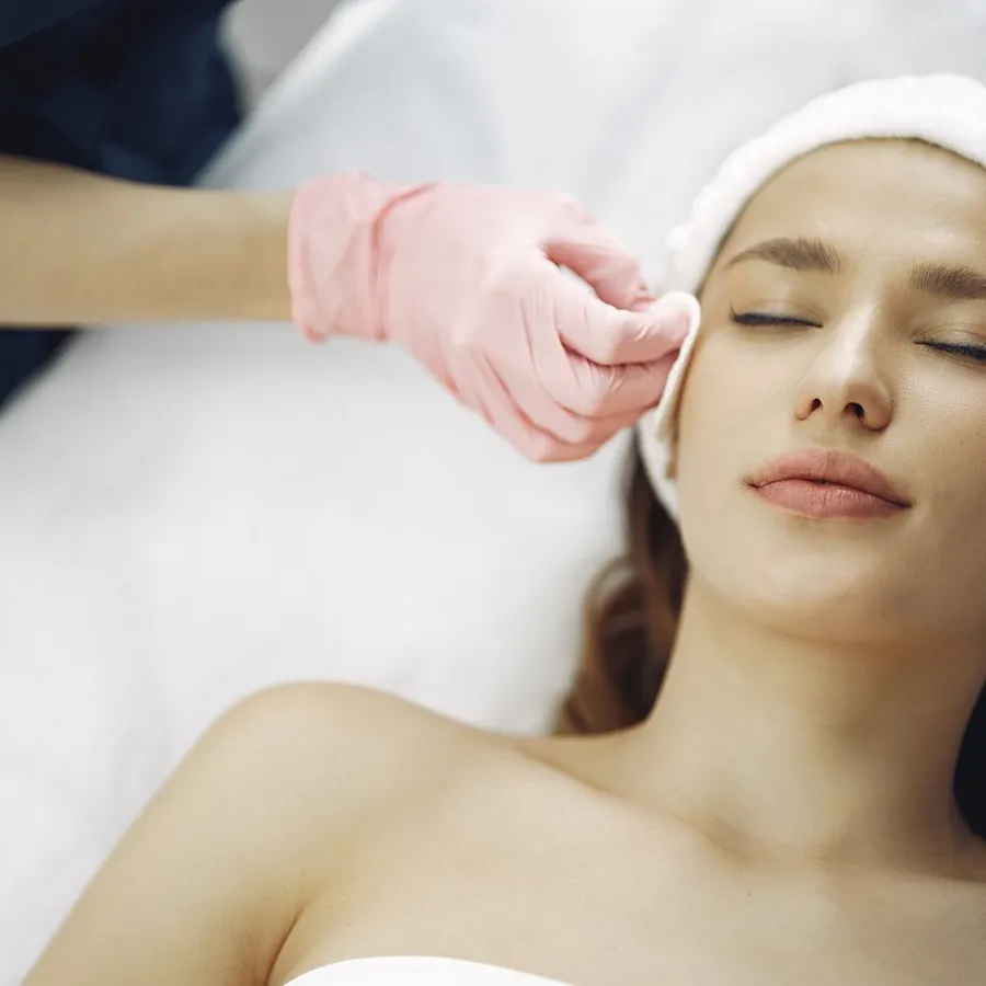 A client resting with eyes closed during a facial, a white headband holding back her hair