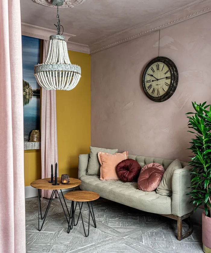 A cozy waiting nook with a velvet sofa, cushions and a wall clock