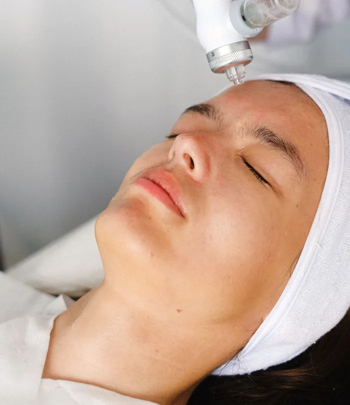 A handheld device moving along a client's hairline as she rests on the table