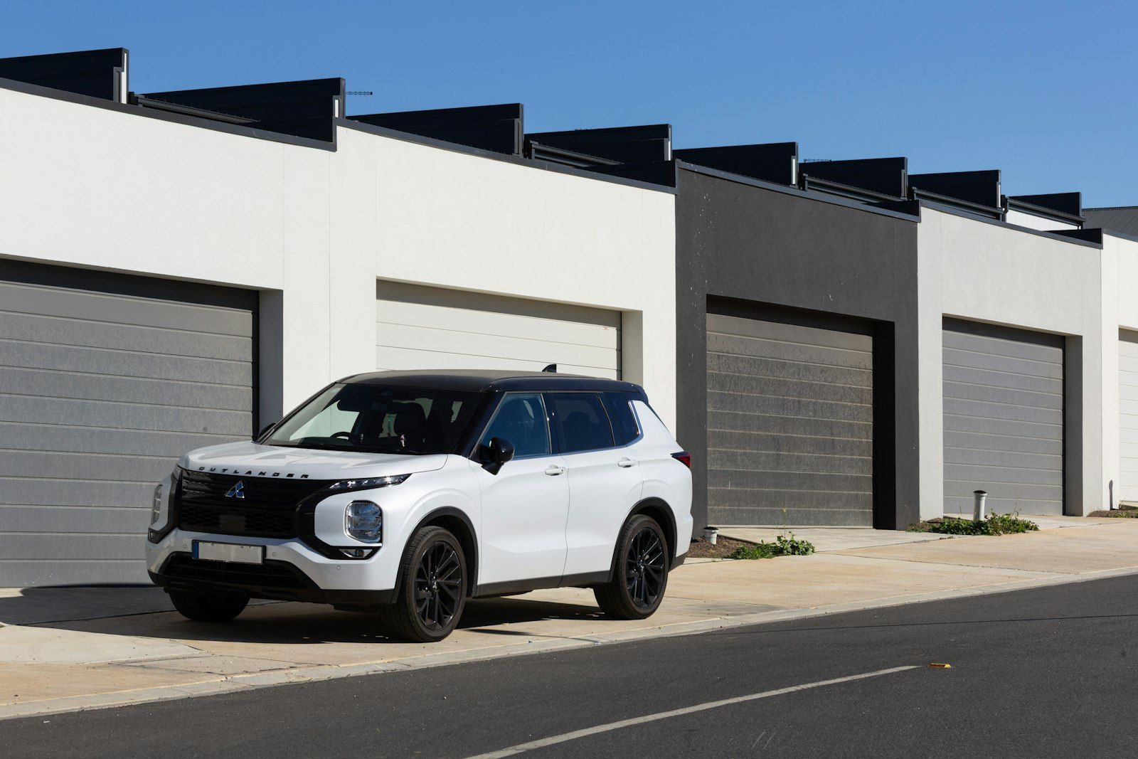 White SUV with dark tinted windows parked in front of garages