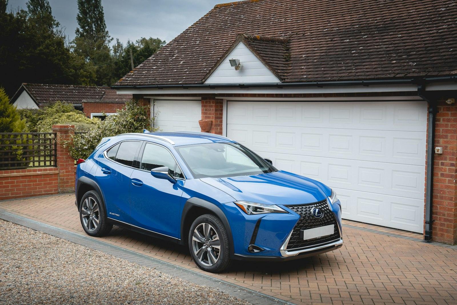 Blue crossover with tinted windows on a brick driveway