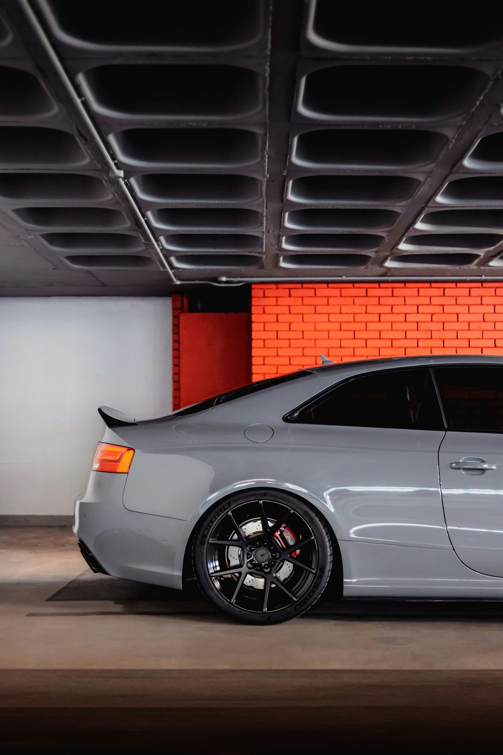 Gray sports sedan with tinted windows parked in a garage