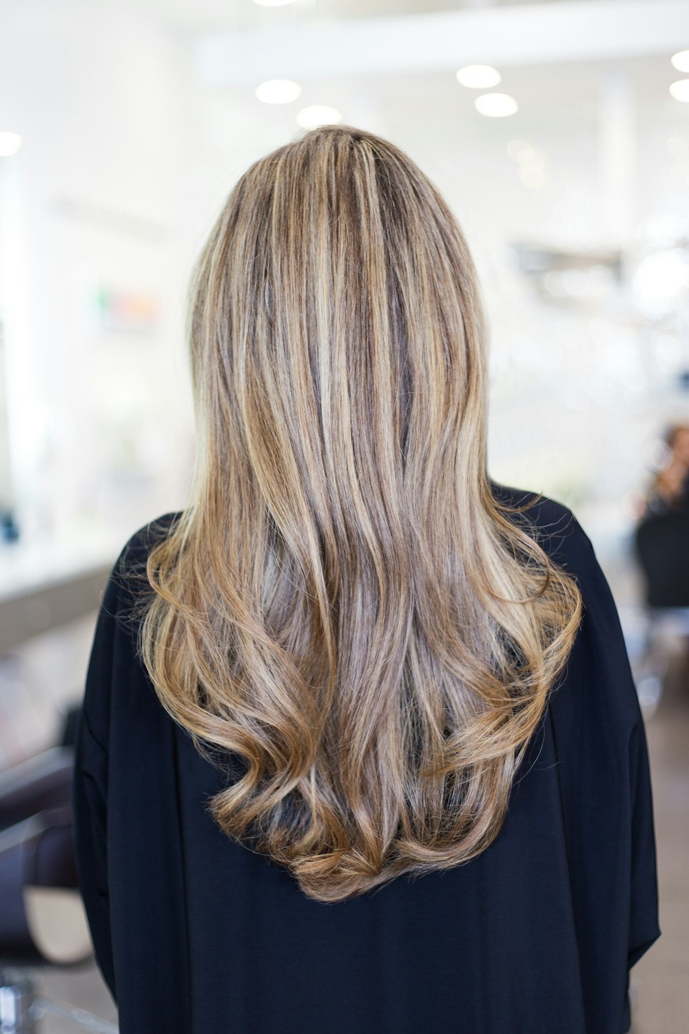 Long blended blonde waves with a darker root, seen from behind